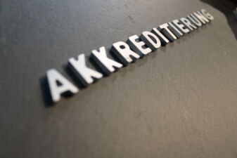 Auf einer Steinoberfläche steht in Großbuchstaben das Wort "Akkreditierung"